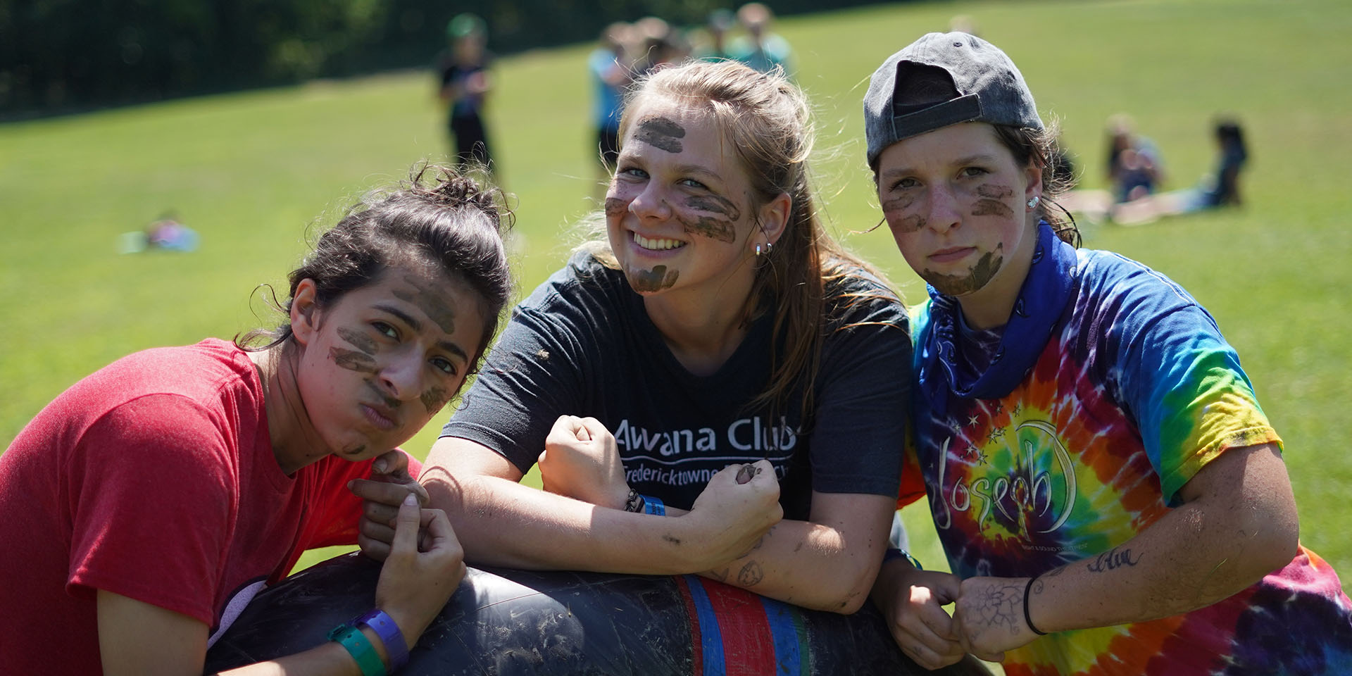 Three campers pose together with mud painted on their faces.